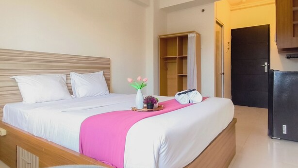 A hotel room with a bed, a wardrobe, a door, and a refrigerator. - Restful And Warm Studio At Apartment Menara Rungkut (Surabaya)