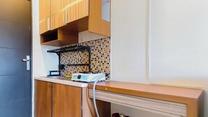 A kitchen with wooden cabinets, a tiled backsplash, and a gas stove. - Restful And Warm Studio At Apartment Menara Rungkut (Surabaya)