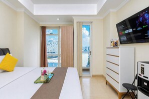 Habitación de hotel con cama, televisión, escritorio y vistas a la ciudad.