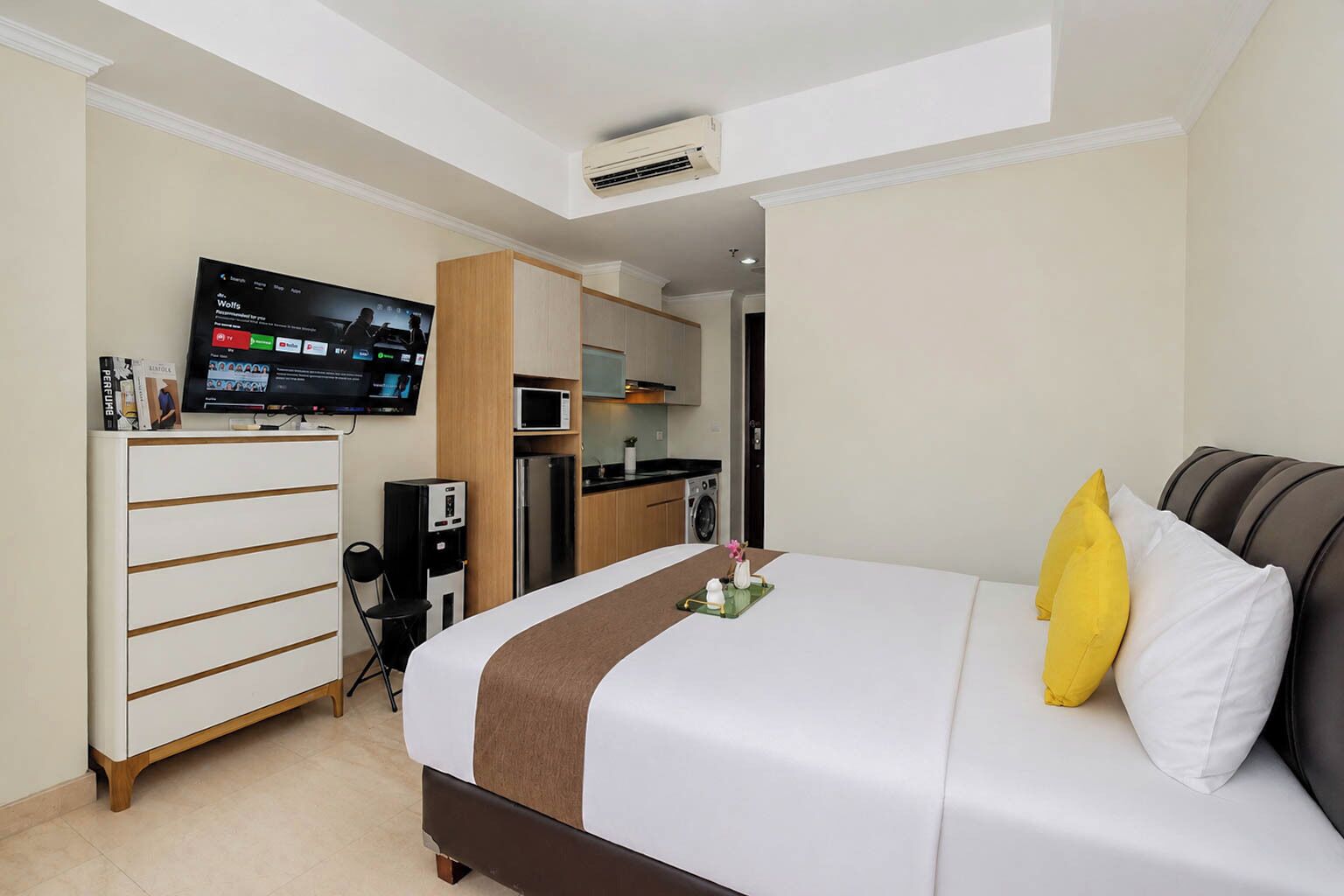 Una camera d'albergo con un letto, una televisione, un angolo cottura e una scrivania con una sedia.