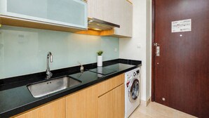 Una cocina compacta con un lavabo, lavadora y un armario.