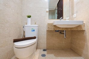 Un baño pequeño con inodoro, lavamanos y una planta pequeña sobre el tanque del inodoro.