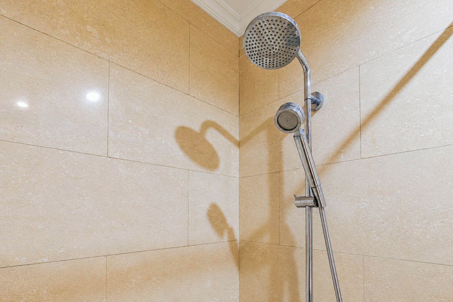 Eine Dusche mit Handbrause und am Wand montiertem Wasserhahn.