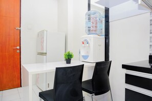 Eine kleine Küchenzeile mit Kühlschrank, Wasserspender und einem Blumentopf.