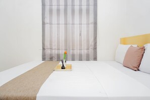 Ein Hotelzimmer mit Bett, Nachttisch und Kerze, sowie einem gestreiften Vorhang.