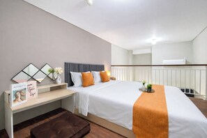 Ein modernes Hotelzimmer mit Bett, Nachttisch und einer kleinen Sitzecke.