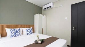 A hotel room with a bed, a wardrobe, an air conditioning unit, and a bedside table. - Functional Designed 2Br Apartment At Nifarro Park (Jakarta)