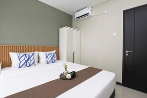 Une chambre d’hôtel équipée d’un lit, d’une armoire, d’un climatiseur et d’une table de chevet.
