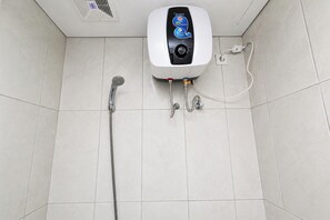 Ein Badezimmer mit Durchlauferhitzer, Handbrause und Steckdose.