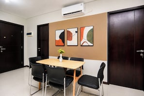 A conference room with a table, chairs, and artwork on the wall. - Roomy Urban Living In 3Br At Apartment Nifarro Park (Jakarta)