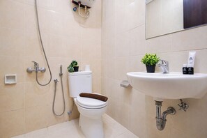 A bathroom with a toilet, bidet, shower, sink, and a small potted plant. - Roomy Urban Living In 3Br At Apartment Nifarro Park (Jakarta)