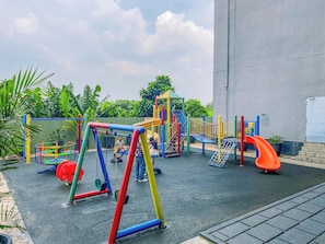 A playground with various play structures including swings, slides, and climbing areas. - Roomy Urban Living In 3Br At Apartment Nifarro Park (Jakarta)