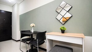 Ein modernes Zimmer mit Schreibtisch, zwei Stühlen, einem kleinen Tisch mit Vase und Pflanze sowie einer dekorativen Wandarbeit.
