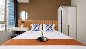 Hotelkamer met een bed, nachtkastje, spiegel, kledingkast en raam met uitzicht op gebouwen.