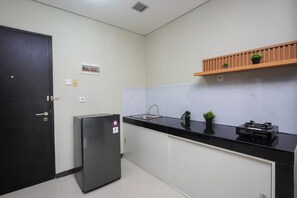 Eine Küche mit einem schwarzen Kühlschrank, einer Spüle und einem Holzboden mit Pflanzen.