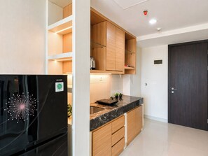 Eine moderne Küche mit Holzausstattung, einem schwarzen Kühlschrank und einer Marmorarbeitsplatte.
