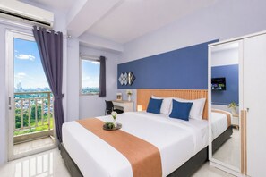 Ein Hotelzimmer mit Bett, Schreibtisch, Stuhl, Fernseher und Blick auf die Stadt.