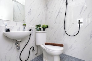 A bathroom with a white toilet, a sink, and a shower.