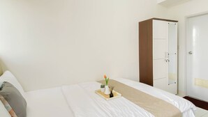 Habitación de hotel con cama, mesita de noche con bandeja, armario y puerta.