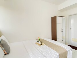 Habitación de hotel con cama, mesita de noche con bandeja, armario y puerta.