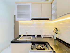 Una cucina moderna con un piano di lavoro nero, lavello in acciaio inossidabile, mobili bianchi e piano cottura integrato.
