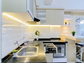 Una cocina moderna con un lavamanos de acero inoxidable, un horno empotrado y un lavavajillas compacto.