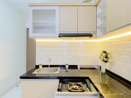 Una cocina moderna con encimera negra, pileta de acero inoxidable, armarios blancos y estufa integrada.