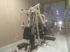 Ein Fitnessraum mit Trainingsgeräten, einer Bank und einem großen Fenster.
