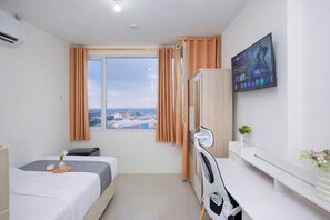 A hotel room with a bed, a desk, a chair, a TV, and a window with curtains. - Comfortable And Decent Studio Room At Apartment Saladdin Mansion (Depok)
