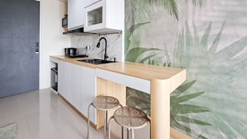 A modern kitchen with a wooden countertop, two stools, a microwave, and a stove.