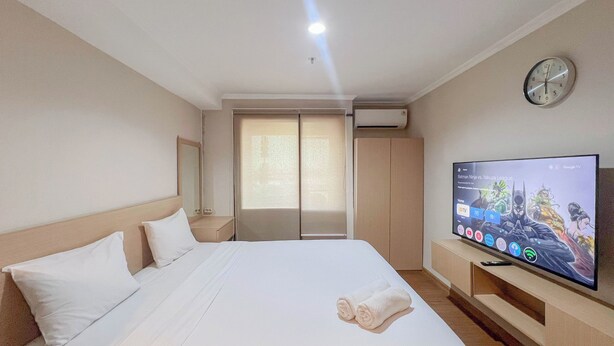 A hotel room with a bed, a TV, a clock, and a window with blinds. - Compact Studio Apartment For 2 Pax At Sentraland Medan (Medan)