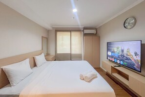 A hotel room with a bed, a TV, a clock, and a window with blinds. - Compact Studio Apartment For 2 Pax At Sentraland Medan (Medan)