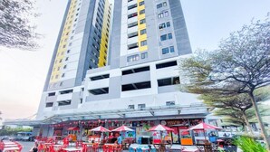 A multi-story building with a commercial ground floor featuring outdoor seating and a covered area. - Compact Studio Apartment For 2 Pax At Sentraland Medan (Medan)