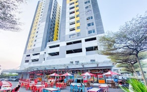 A multi-story building with a commercial ground floor featuring outdoor seating and a covered area. - Compact Studio Apartment For 2 Pax At Sentraland Medan (Medan)