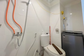A bathroom with a toilet, a shower with a hose, and a trash bin. - Compact Studio Apartment For 2 Pax At Sentraland Medan (Medan)