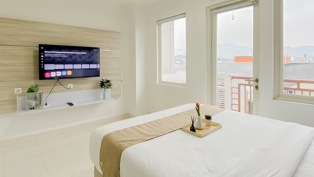 Habitación de hotel con una cama, televisor montado en la pared, ventana y unidad de aire acondicionado.