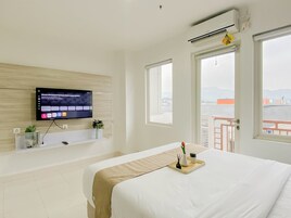 Habitación de hotel con una cama, televisor montado en la pared, ventana y unidad de aire acondicionado.