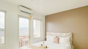 Una habitación de hotel con cama, mesita de noche, ventana y aire acondicionado.