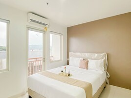 Una habitación de hotel con cama, mesita de noche, ventana y aire acondicionado.