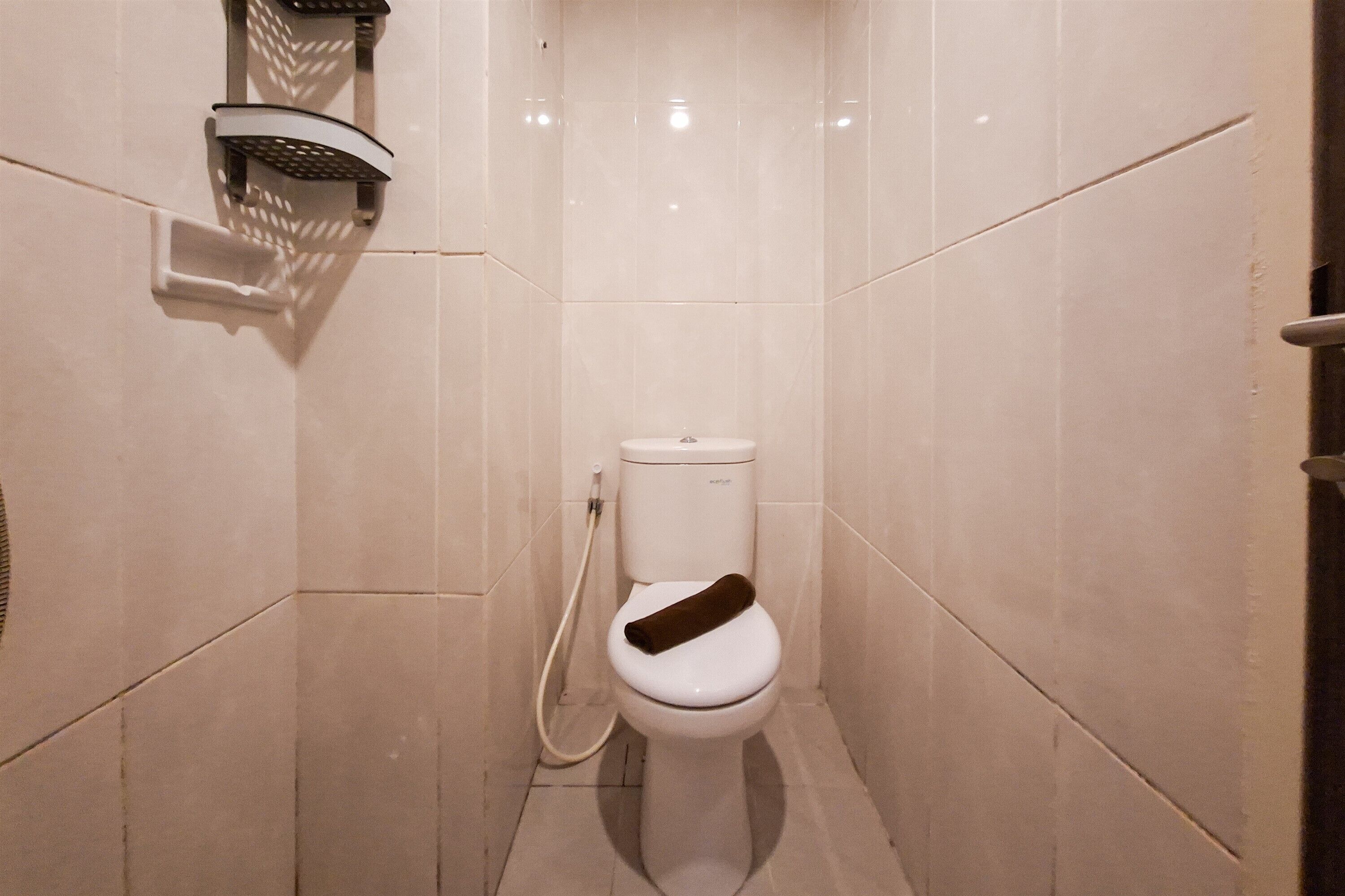 Pieni, moderni kylpyhuone, jossa on wc, suihkupää ja pyyheteline.