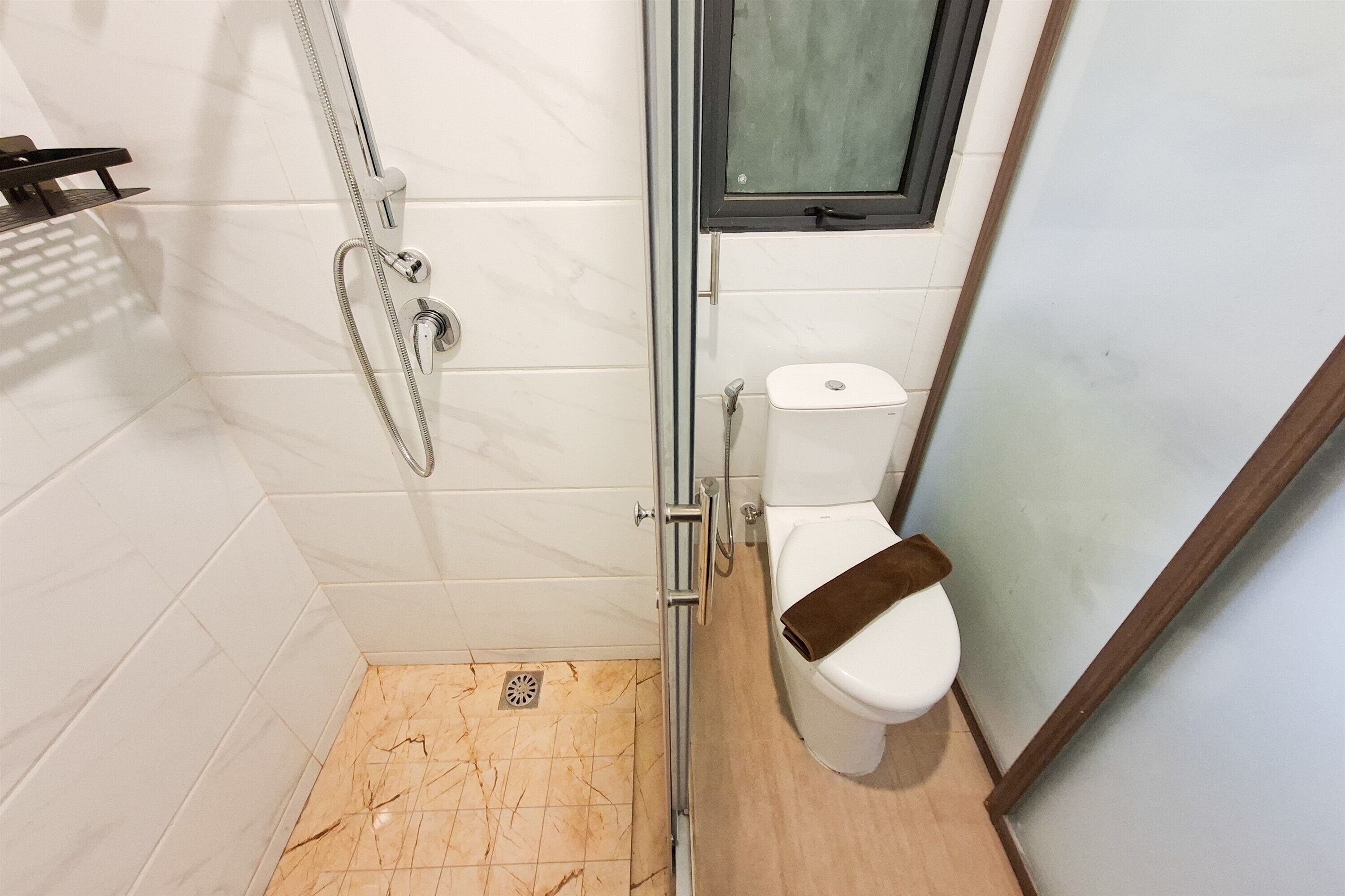 Un baño con ducha, inodoro y ventana.