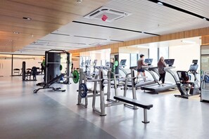 Un gimnasio con cintas de correr, máquinas de pesas y un banco.