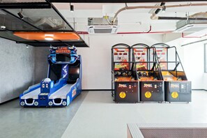 En indendørs spillehal med et racerbilspil, et basketballspil og en kranarm.