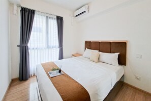 Ein Hotelzimmer mit einem Bett, einem Nachttisch, einer Klimaanlage und einem Fenster mit Vorhängen.