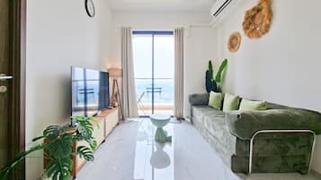 Una sala de estar moderna con televisor de pantalla plana, un sofá, una mesa de centro y una planta en maceta.