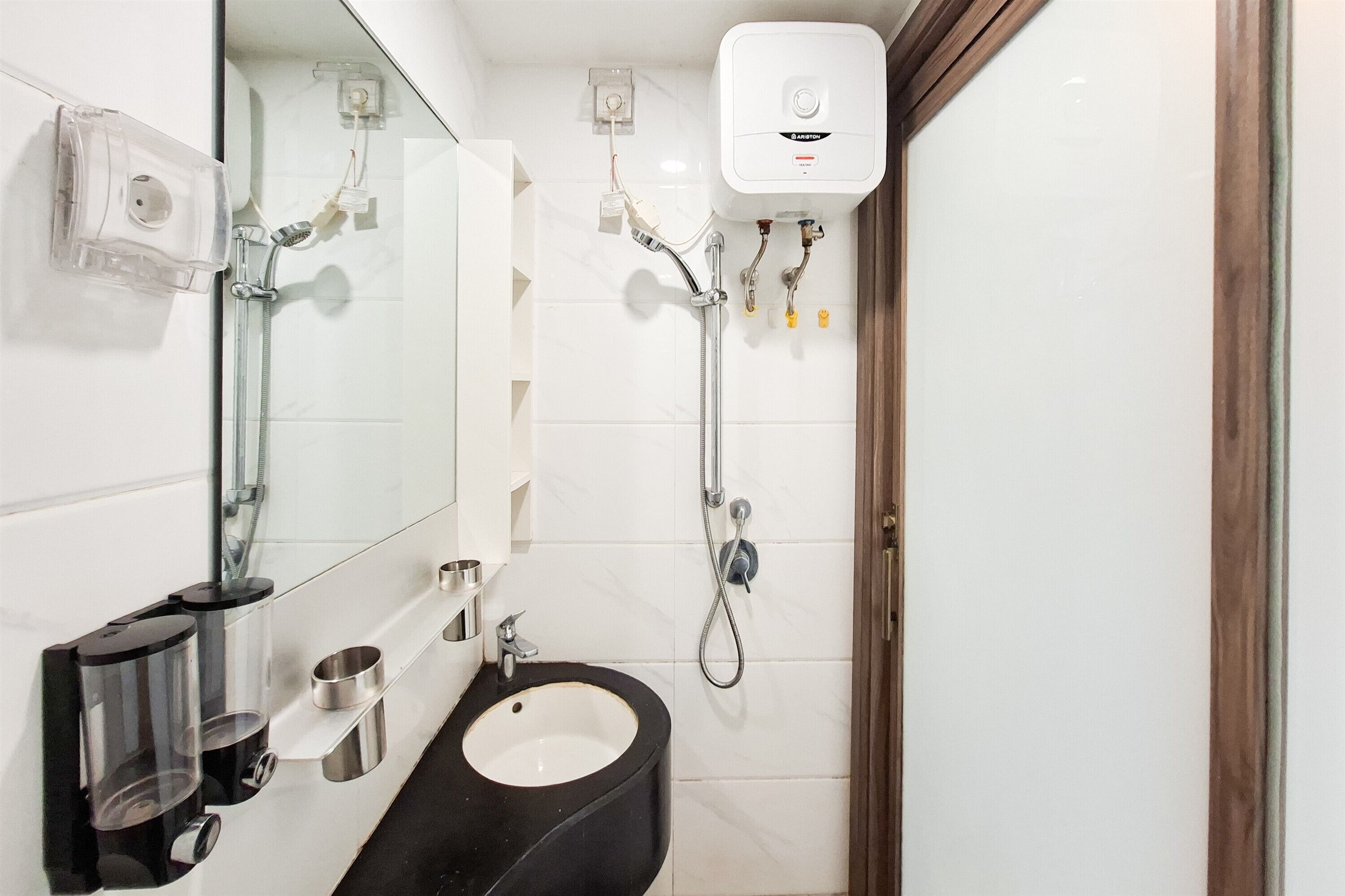Un baño moderno con un lavabo negro, cabina de ducha con paredes de vidrio y un inodoro blanco.