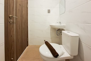 Ein Badezimmer mit Holztür, weißen Fliesen, einem Waschbecken und einer Toilette mit Handtuch.