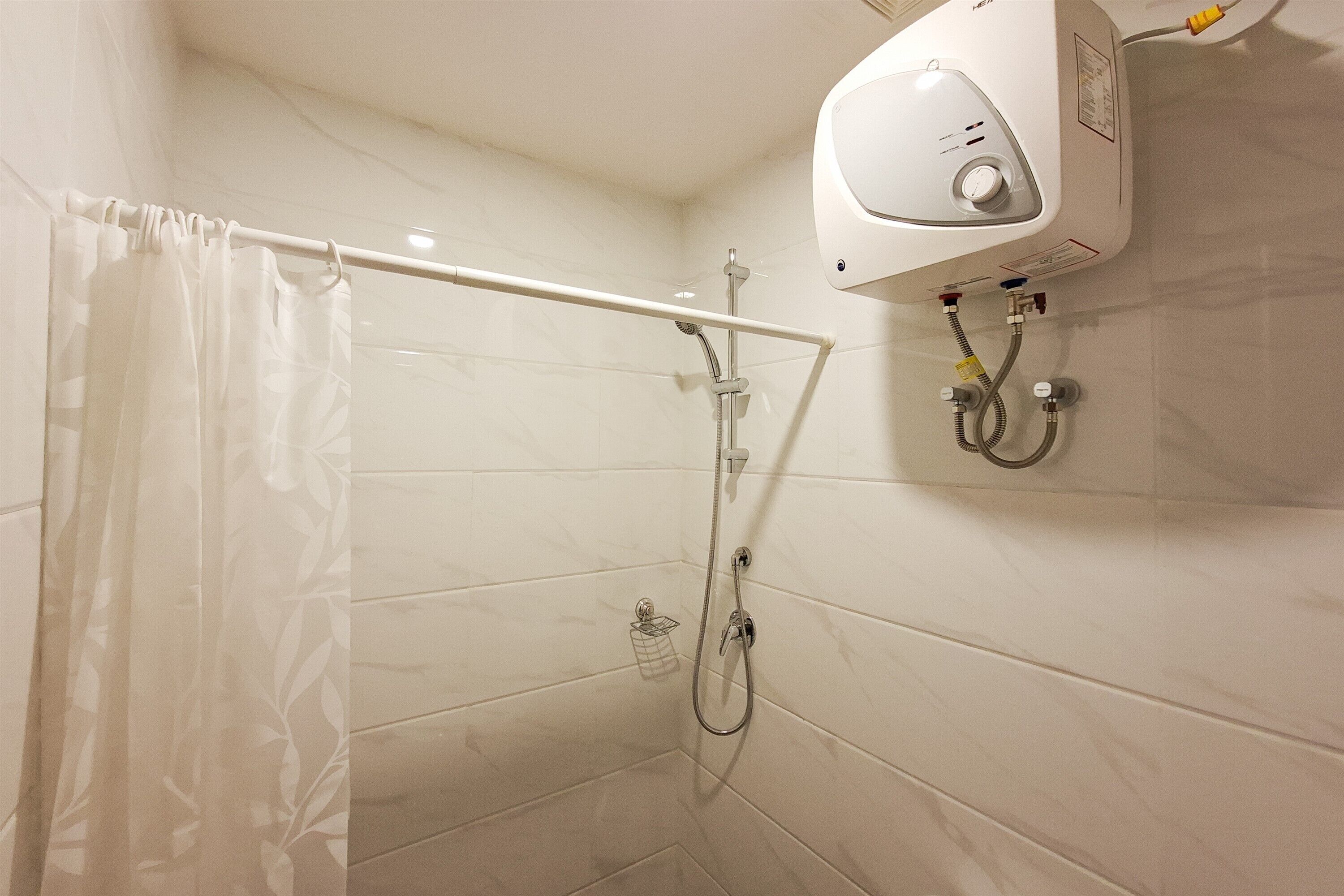 A shower with a white curtain, a handheld showerhead, and a wall-mounted control panel.