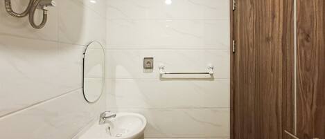 A bathroom with a white sink, mirror, and shower.