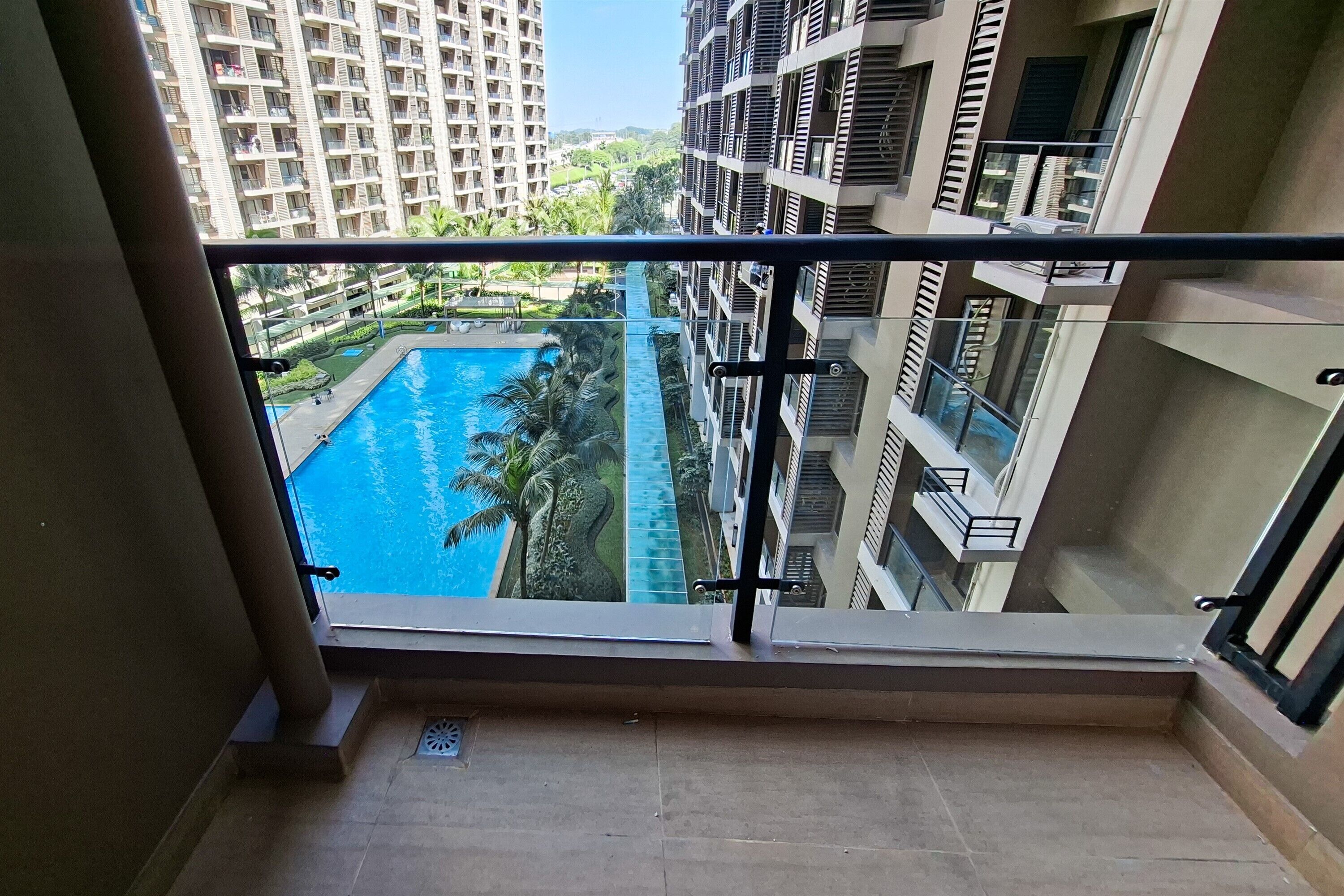 A balcony with a view of a swimming pool and high-rise buildings.